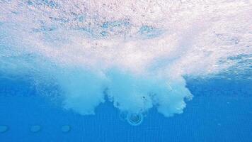 Bubbles rising to the surface. Air bubbles in clear blue water in pool. Many bubbles in the water of the swimming pool. Close-up. video