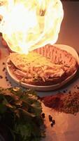 Juicy sandwich on a baguette with cheese and vegetables and meat is effectively fried using an open fire to melt the cheddar during cooking. Top view. Slow motion. Vertical video
