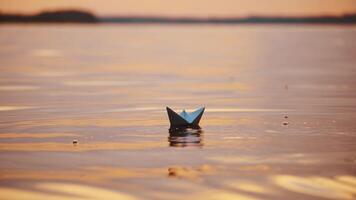 Paper ships on water surface at sunset. One origami boat floating in the river and another one joins to it. video