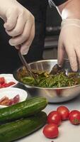 Chef in restaurant's kitchen is preparing salad with fresh herbs and honey mustard dressing. chef is manually mixing the greens with his hands to ensure that salad is adequately seasoned with sauce. video