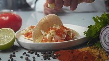 Ready to serve customer, seafood tacos are sprinkled with lemon juice, squeezed from cut piece of lemon. This gives the dish tangy flavor. video