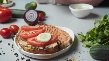 Cook prepares toast with various vegetables and cheese, including cucumbers and tomatoes, as well as potato sauce video