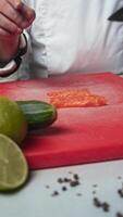 The cook carefully slices the tender salmon fillet on a chopping board with a sharp professional knife. Vertical video