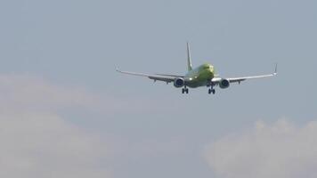 Unrecognizable aircraft with green livery approaching landing, long shot. Plane flying, front view video
