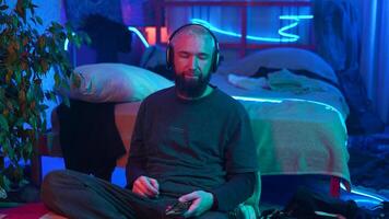 A guy in a neon room listening to music alone and relaxing. Media. Room of a teenager and mess. video