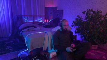 Man using smartphone and listening to music at home. Media. Cozy and messy room of a hipster guy. video
