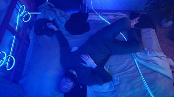 Top view of a sleepy man with neon lighting. Media. Young bearded man feeling tired and trying to sleep, lying on bed. video