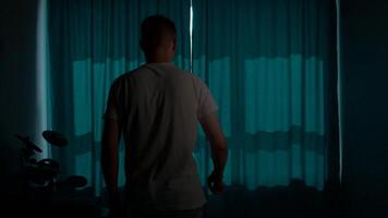Silhouette of man opening curtains and looking out of window in the morning, concept start of the day. Media. Young man stretching and looking through the window. video
