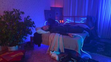 Man listening to music, using headphones in bedroom at night. Media. Man lying on his bed and enjoying music. video