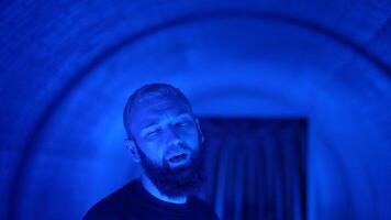Portrait of a young stylish hipster man rapper moving and posing to the camera. Media. Neon lighting background creating effect of spinning tunnel. video