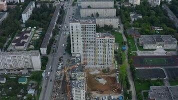 Top view of construction of multi-storey building in city. Stock footage. Construction of multi-storey building in city center on summer day. Panorama of modern city with construction of high-rise video