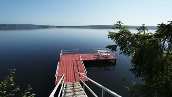 The tranquil lake dock is beautifully surrounded by lush greenery in a serene location. Clip video
