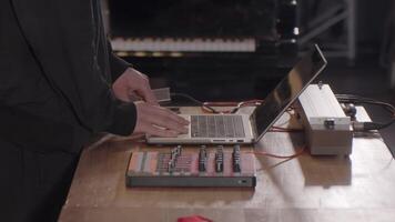 A musician creatively engages with various electronic equipment in a studio environment. Clip video