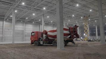 A busy construction site with a concrete mixer in a warehouse, emphasizing building activities. Clip video