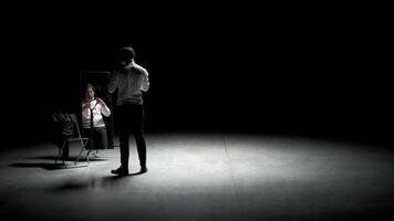 Man in suit in front of mirror. Stock footage. Man on stage with mirror puts on suit. Stage production with one man and mirror on dark stage video