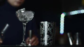 Close up of glass with ice cubes prepared for cocktail. Media. Bartender mixing alcohol liquids in a shaker. video