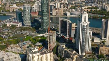 Top view of construction of building in city center with high-rise buildings. Stock footage. Landscape of city with high-rise buildings and building under construction in center. Beautiful summer video
