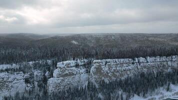 Aerial view of mountain cliff and river. Clip. Frosty cold snowy morning and the endless evergreen pine forest. video