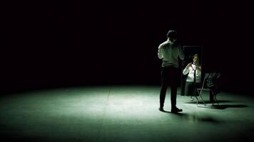 Man in suit in front of mirror. Stock footage. Man on stage with mirror puts on suit. Stage production with one man and mirror on dark stage video