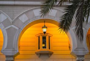 Beautiful wall background with an arch illuminated by the light of a vintage lamp and palm leaves. photo