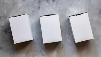 Three white closed cardboard boxes on gray backdrop. Craft eco package. Flat lay photo