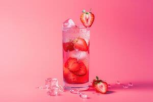A Glass of Sparkling Strawberry Lemonade with Ice Cubes and Strawberries on a Pink Background photo