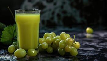 A glass of green grape juice with green grapes and a leaf photo