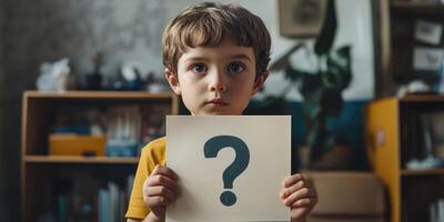 The child is holding a paper with a question mark on it. Selective focus. Kid. photo