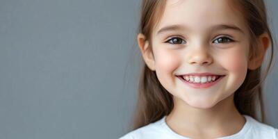 Happy girl. Close-up portrait of a cheerful child smiling, isolated against a grey background. photo