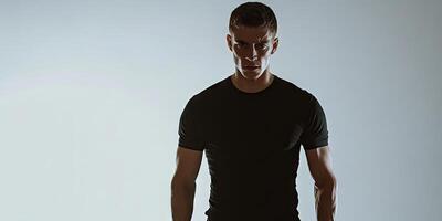 A man in a black T-shirt is standing in front of a white background, appearing unwell while posing. photo