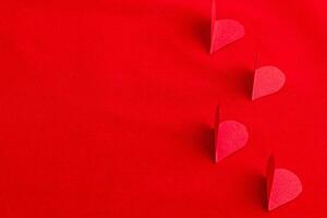 Hand cut paper hearts on a red background photo