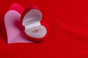 heart shaped ring with diamonds on a hand cut paper heart on a red background photo