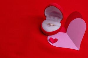 heart shaped ring with diamonds on a hand cut paper heart on a red background photo