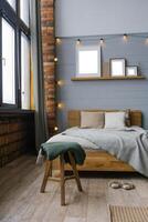 Green blanket on the stool by the bed in the bedroom in the Scandinavian style photo