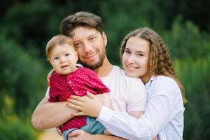 A happy young beautiful family with a young son is enjoying a wonderful day in the summer park photo