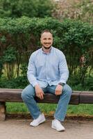 Attractive smiling man sitting alone on a park bench photo