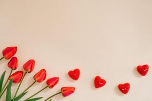Flat lay valentines day frame with red tulips and and red heart on a light background with copy space photo