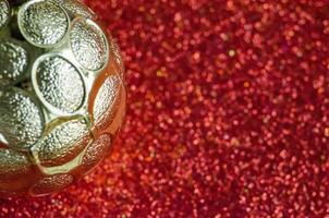 Close up of Golden Christmas ball on red background with customizable space for text or for wishes. photo