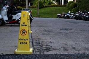 Yellow plastic cone with black letters word no parking three language Thai, English and Japanese on street front building. photo