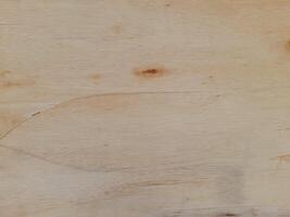A light colored wooden surface with natural grain patterns and subtle knots. Texture is smooth, with some areas displaying faint lines and color variations, giving it an organic and rustic appearance. photo