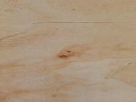 A light colored wooden surface with natural grain patterns and subtle knots. Texture is smooth, with some areas displaying faint lines and color variations, giving it an organic and rustic appearance. photo
