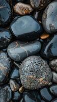 Smooth dark gray pebbles on a beach create a natural texture. Tranquil backgrounds and spa themes photo
