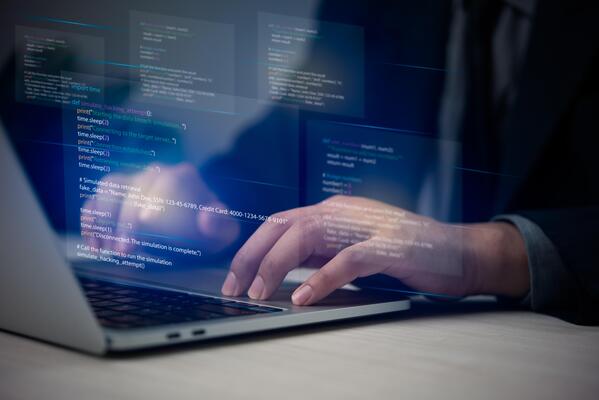 A person in a suit is typing on a laptop