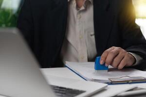 A man in a suit is using a blue rubber to sign a document photo