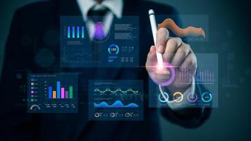 Businessman holding a pen and pointing at a screen with graphs and data photo