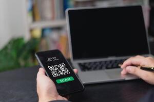 A man using a smartphone to scan a qr code on a laptop photo