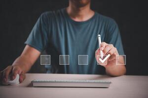 Man writing check mark on computer keyboard photo