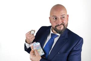portrait of businessman in blue suit and tie with friendly expression showing a watch and banknotes isolated on white background photo