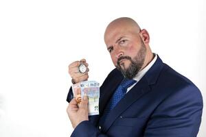 portrait of businessman in blue suit and tie with friendly expression showing a watch and banknotes isolated on white background photo