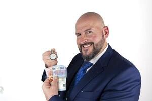 portrait of businessman in blue suit and tie with friendly expression showing a watch and banknotes isolated on white background photo